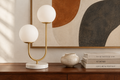 Halo Doppio lamp close-up on a walnut credenza with organic abstract art and ceramic accent